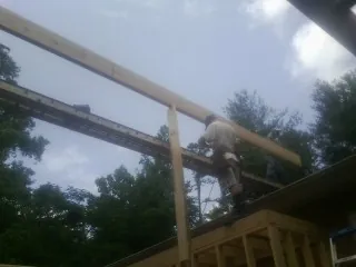 Carpenter setting a ridge beam over a new addition frame — Ice Dam Removal by Roofing Brothers in Berthoud