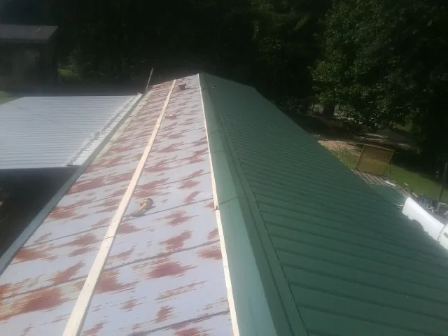 Old rusted panels beside newly installed green metal roofing — Wind Damage Roof Repair by Roofing Brothers in Berthoud