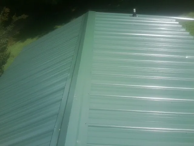 New green metal panels meeting at the ridge of a roof — Flat Roof Repair work by our crew in Berthoud