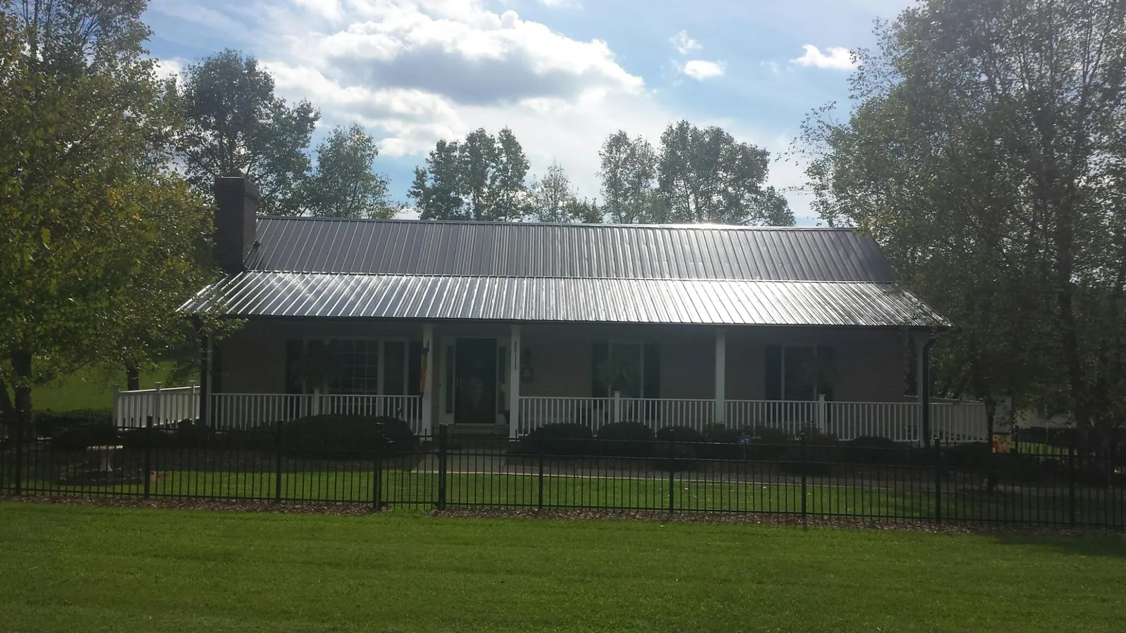 Gray metal roof on a brick ranch with a full width front porch — Gutter Guard Installation work by our crew in Berthoud